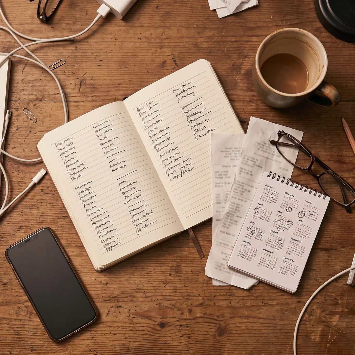Escritorio con un cuaderno anotado a mano, boletas sueltas, un calendario con fechas marcadas y un teléfono: la forma en que hoy se lleva el control de un arriendo.